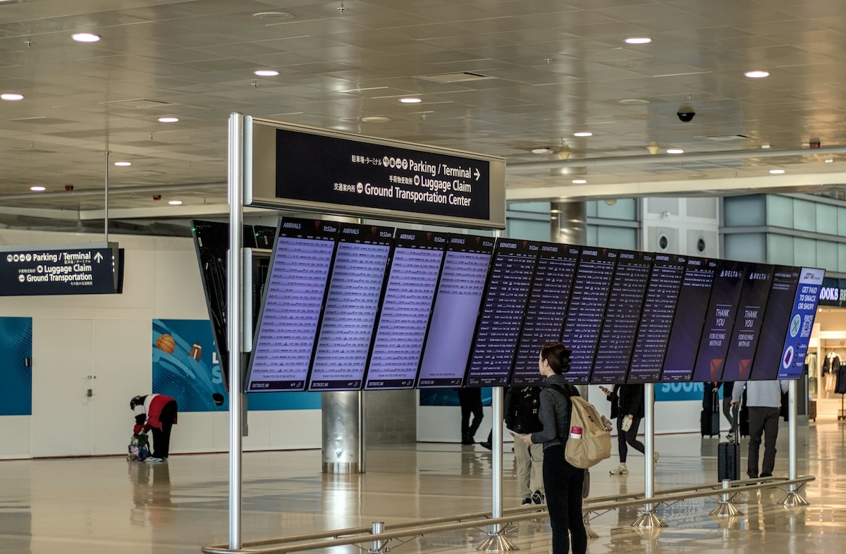 Passenger checking arrivals and departures board at an airport