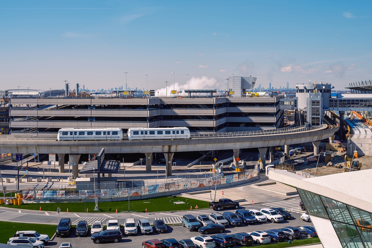 AirTrain connecting terminals at JFK Airport with parking and city skyline in background