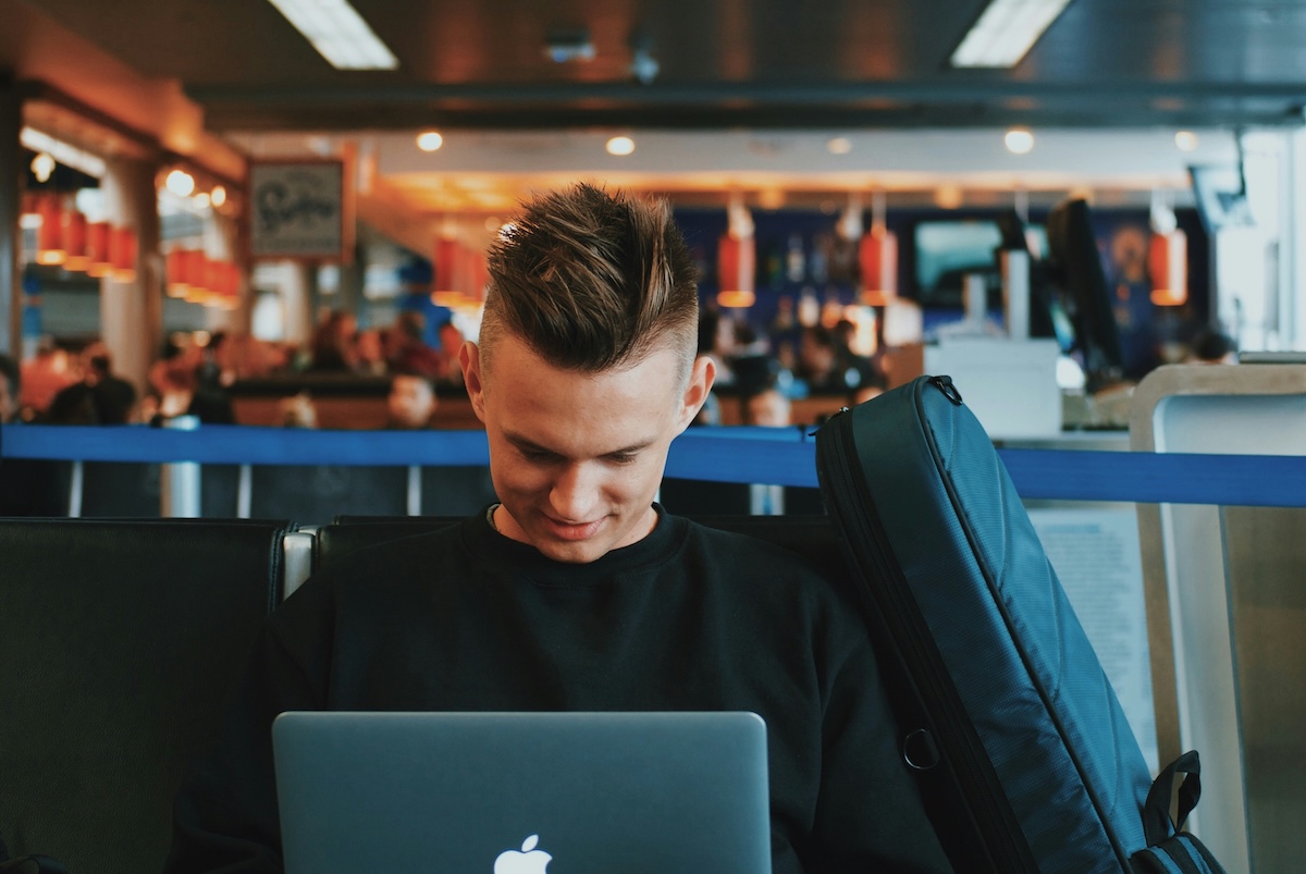 Traveller searching for flights on a laptop at an airport gate